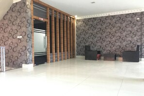 A spacious lobby with a modern design, featuring a patterned wall, a reception desk, and a refrigerator. - Hotel Mulia Tiza (Binjai)