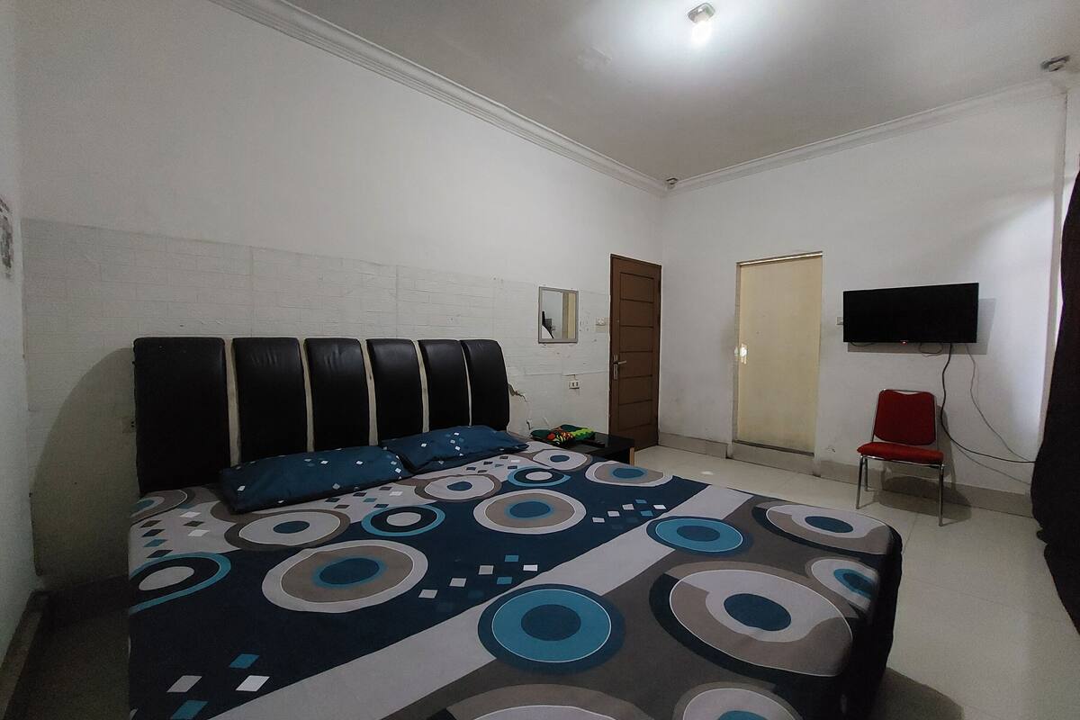 Ein Schlafzimmer mit einem Bett, einem an der Wand befestigten Fernseher und einer Tür.