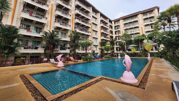 A hotel with multiple balconies, a swimming pool with decorative sculptures, and palm trees. - Landmark Patong Hotel (Patong)