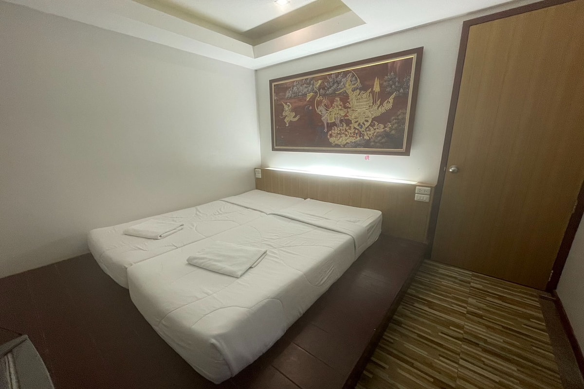A hotel room with a bed, a wall-mounted artwork, and a wooden door.