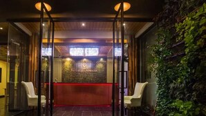 A reception area with a red counter, glass doors, and a wall of greenery. - Landmark Patong Hotel (Patong)