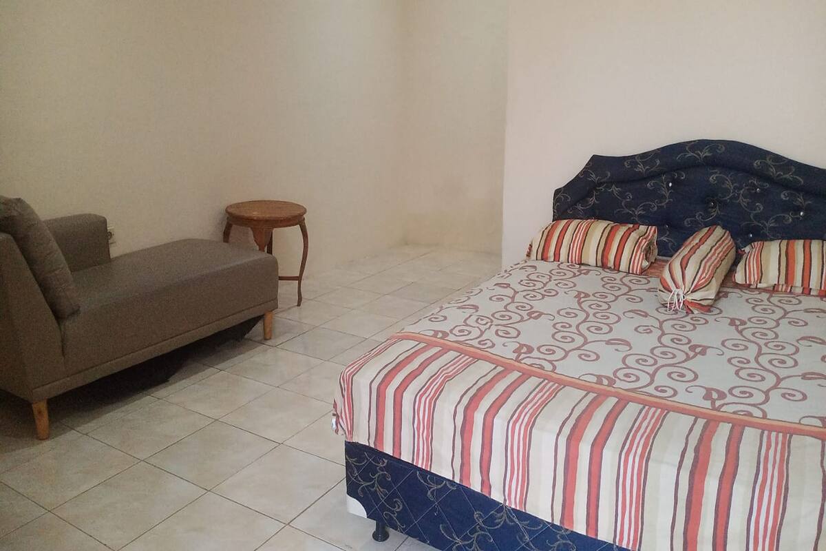 A bedroom with a bed, a sofa, and a small round table.