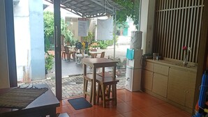 A restaurant with wooden tables and chairs, a tiled floor, and a view of the street outside. - Aryani Suites Syariah (Jakarta)