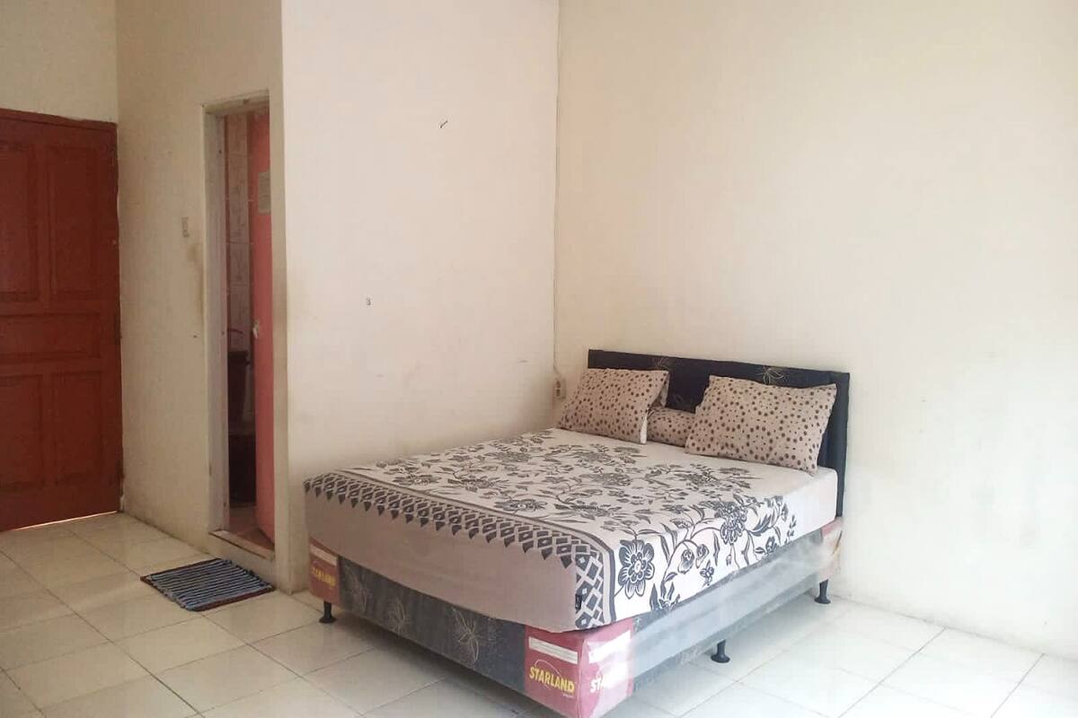 A bedroom with a bed, a door, and a small window.