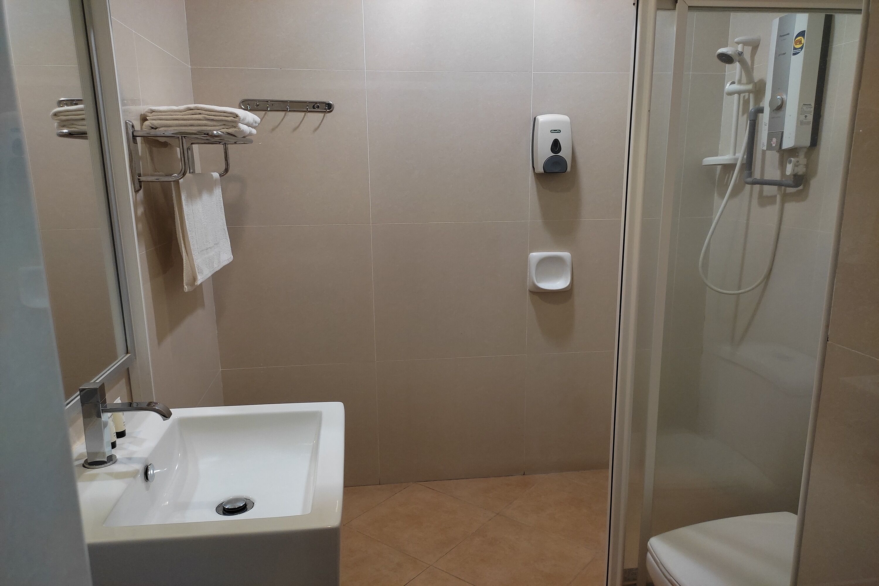 Un bagno con lavandino, porta asciugamani, dispenser per sapone e doccia.