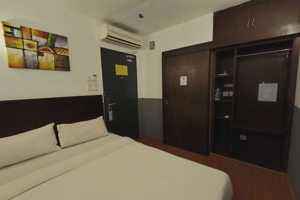 Ein Hotelzimmer mit Bett, Schrank, Klimaanlage und Wandbild.