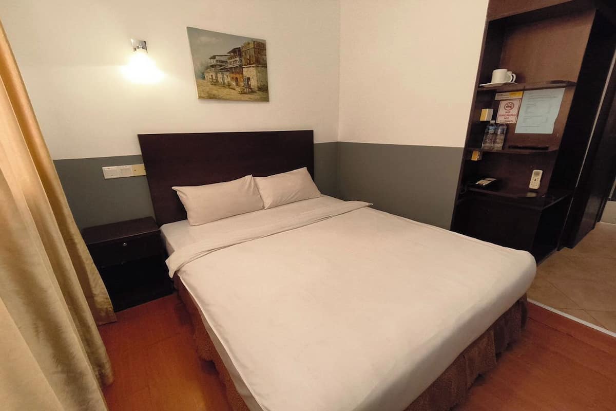 Ein ordentlich bezogenes Bett mit weißen Laken in einem Hotelzimmer.