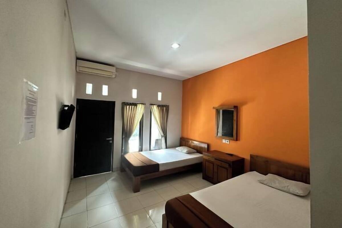 A hotel room with a bed, a desk, a TV, and a window with curtains.