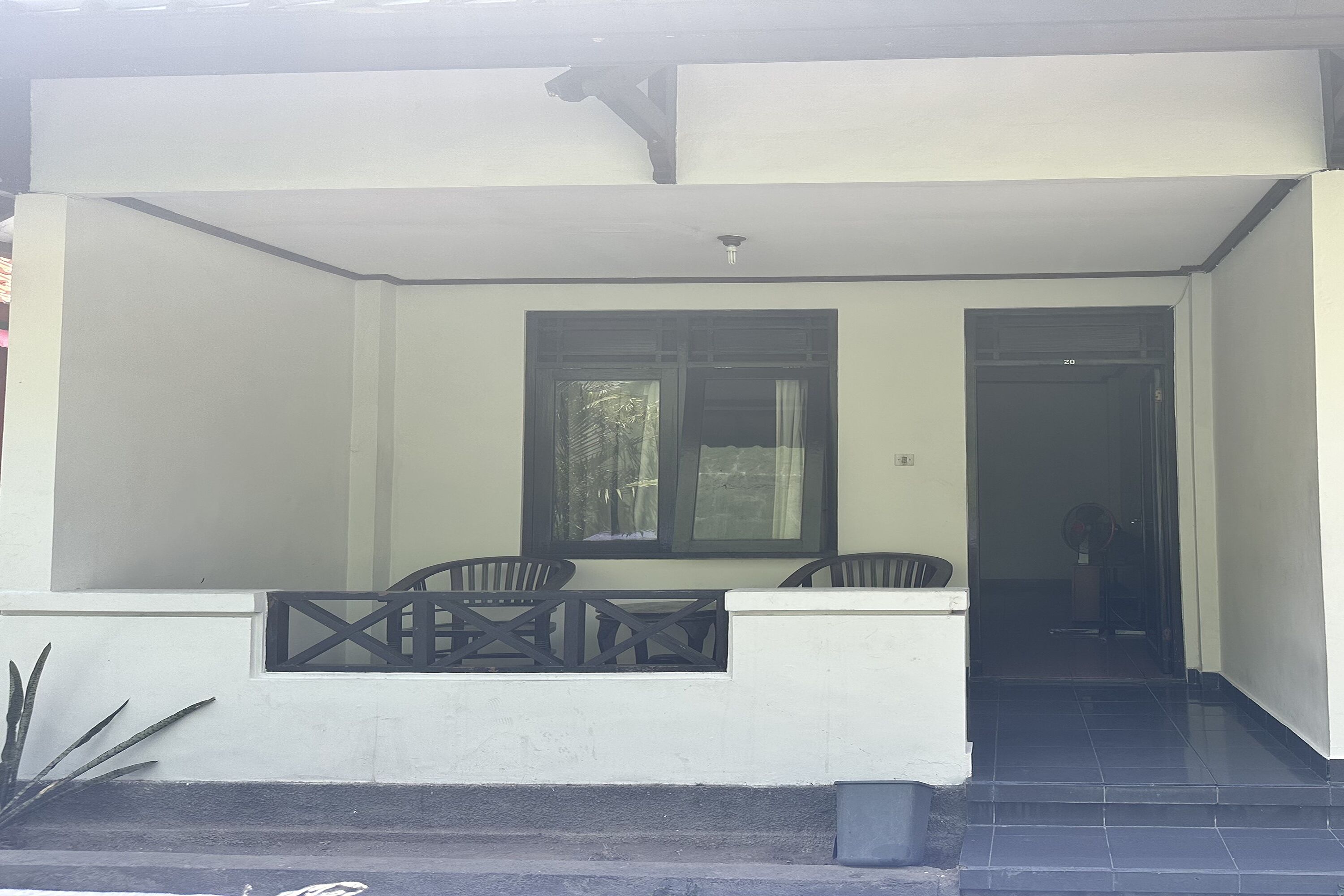 A building entrance with a covered porch, two windows, and a door.
