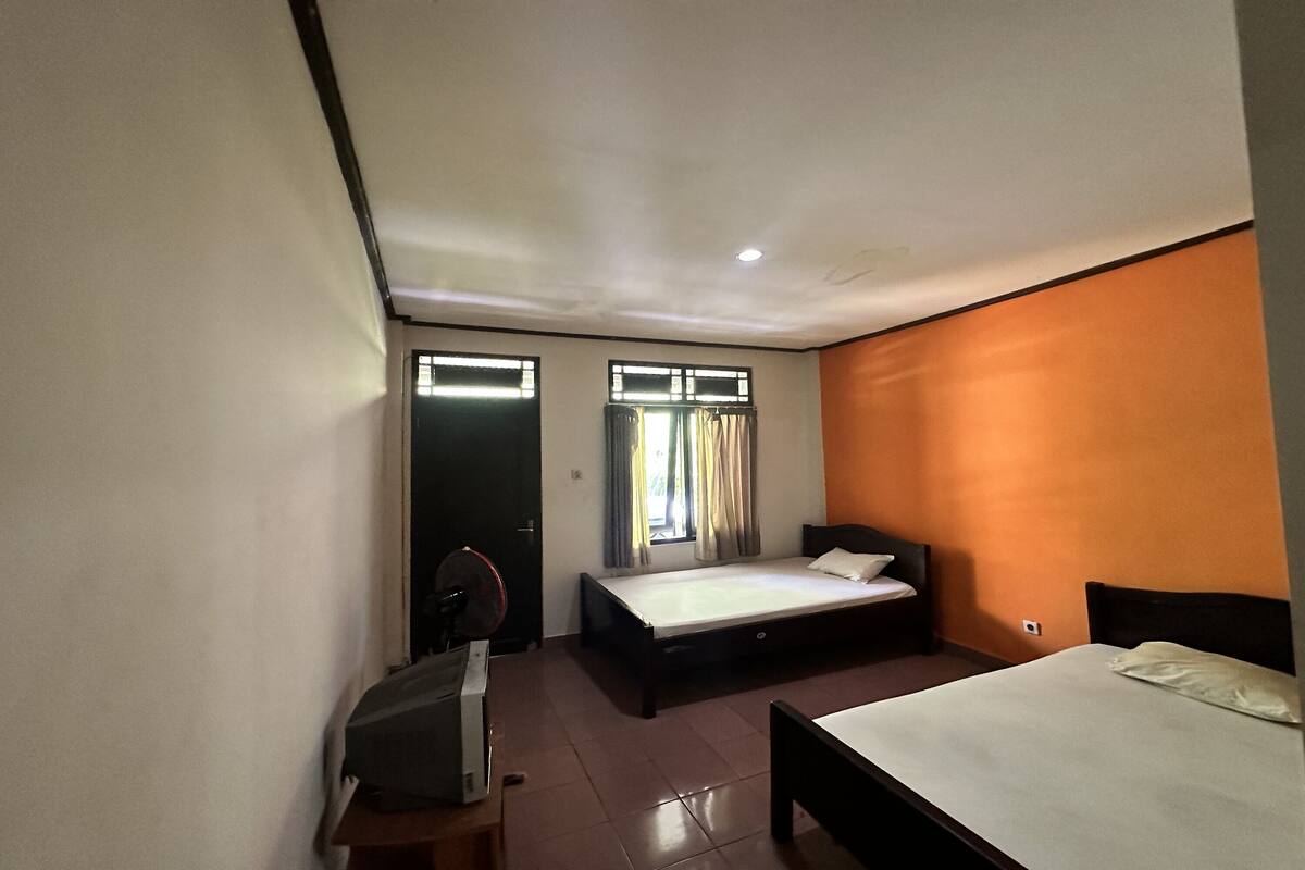 A bedroom with two beds, a desk, and a window with curtains.