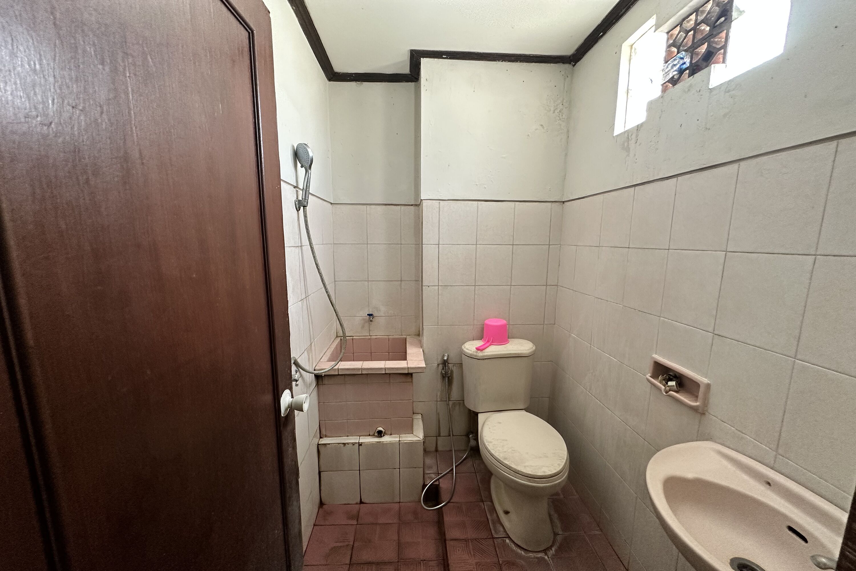 A small bathroom with a toilet, sink, and shower.