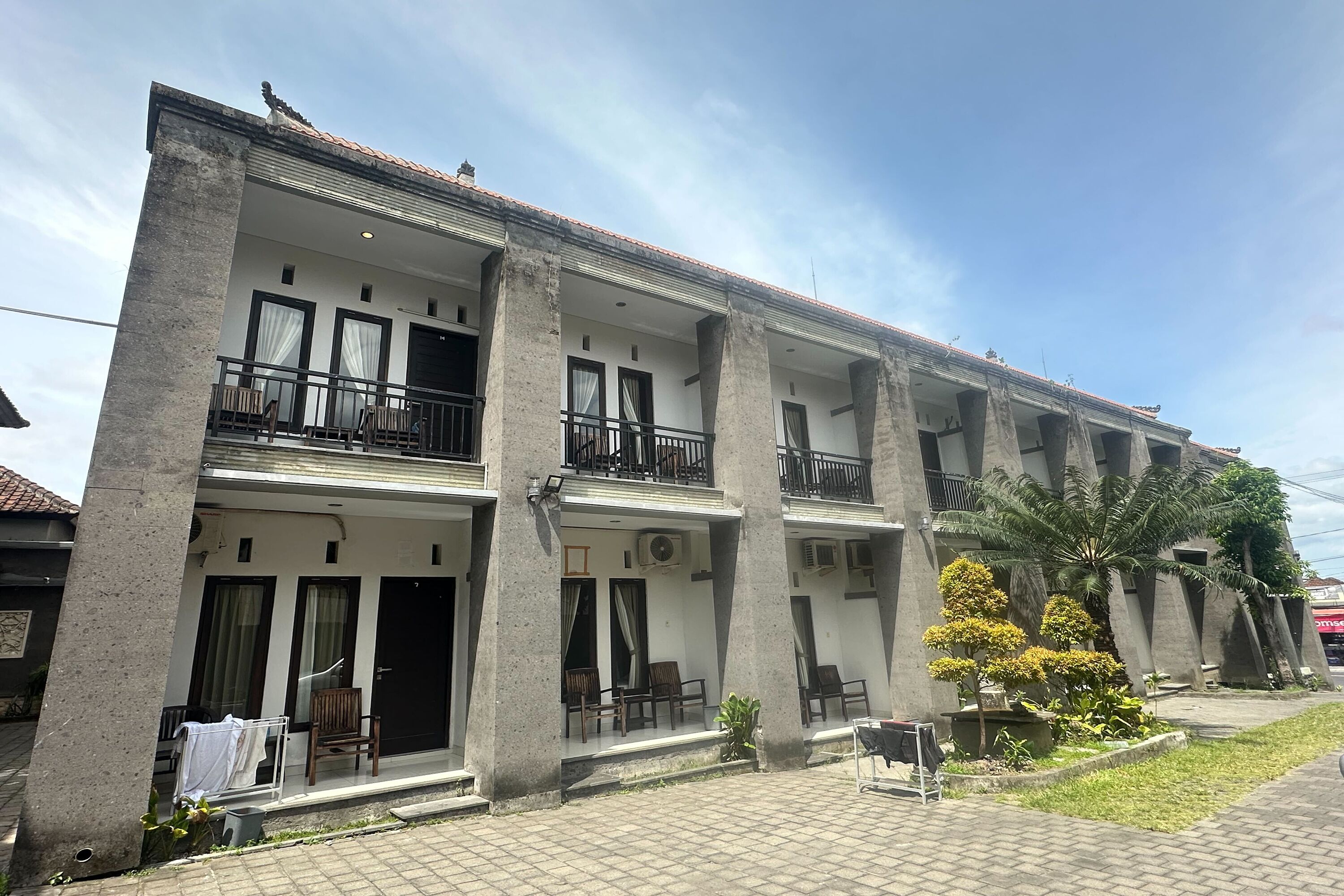 Un edificio de varios pisos con balcones, mobiliario exterior y un jardín.