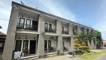 Un edificio de varios pisos con balcones, mobiliario exterior y un jardín.