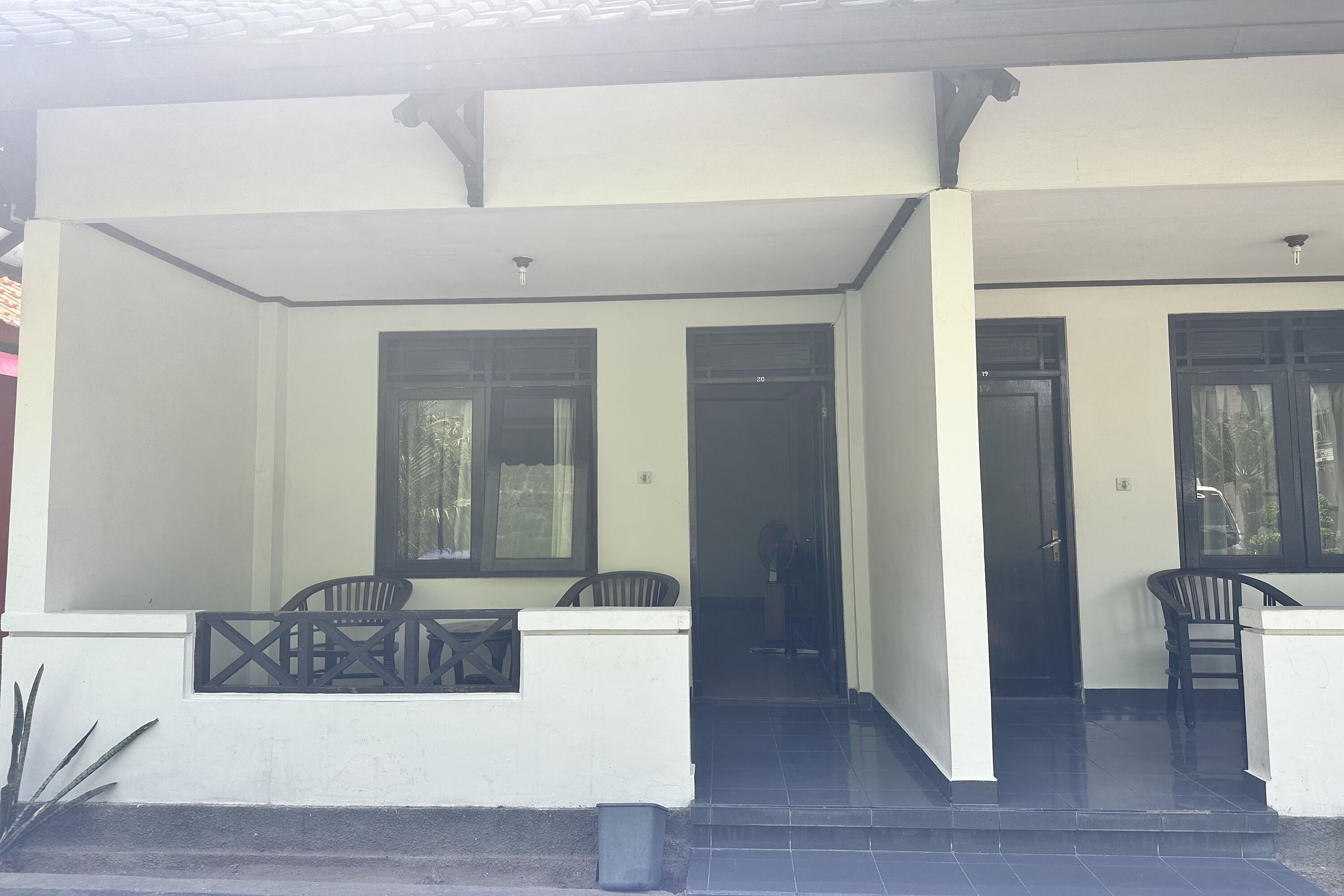 Uma área externa coberta com um conjunto de assentos e uma porta que dá para o interior.