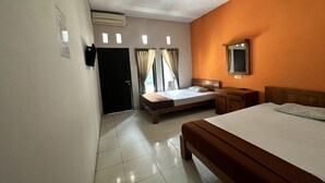 A hotel room with a large bed, a bedside table, a mirror, and a window with curtains. - Hotel Warta Sari (Denpasar)