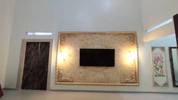 Una habitación con pared de mármol, un televisor de pantalla plana y dos lámparas de pared.