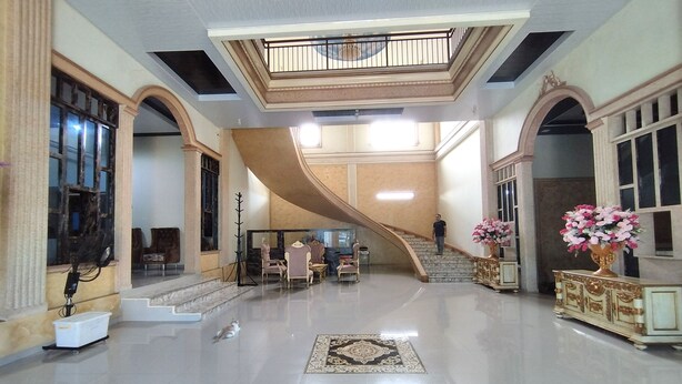 A spacious lobby with a grand staircase, elegant furniture, and decorative vases. - Zahira Guesthouse Syariah (Jambi)