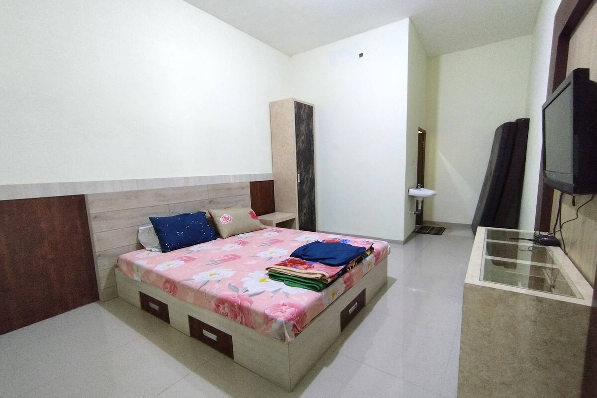 Un dormitorio con cama, armario, televisor y escritorio.