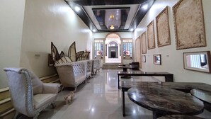 A spacious lobby with a high ceiling, a central staircase, and a seating area with sofas and a coffee table. - Zahira Guesthouse Syariah (Jambi)