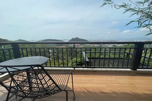 Un balcon avec une table et une chaise, offrant une vue sur le paysage urbain et la verdure.