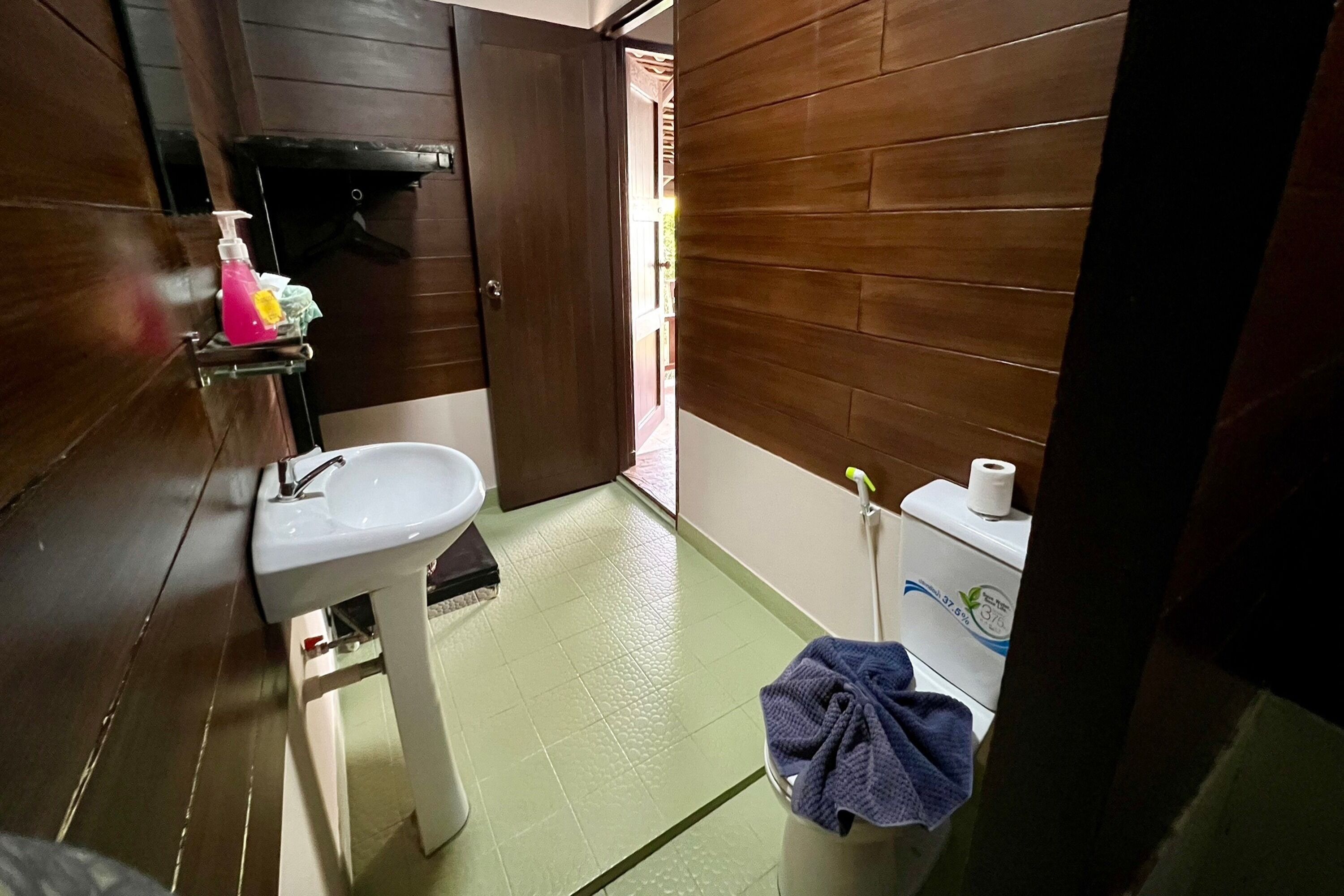 A small bathroom with a white sink, a toilet, and a blue towel on a bucket.