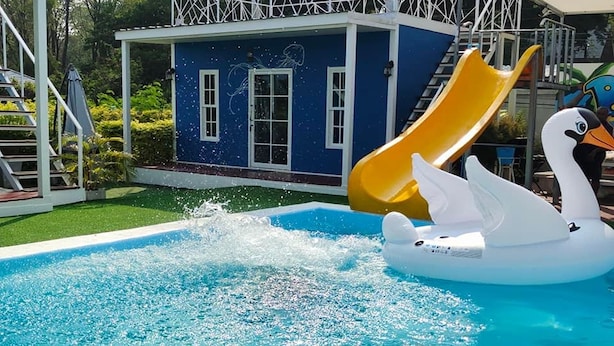 A swimming pool with a water fountain, a slide, and a swan float. - Bluvilla Sattahip (Sattahip)