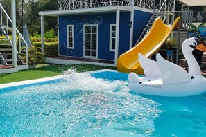A swimming pool with a water fountain, a slide, and a swan float. - Bluvilla Sattahip (Sattahip)