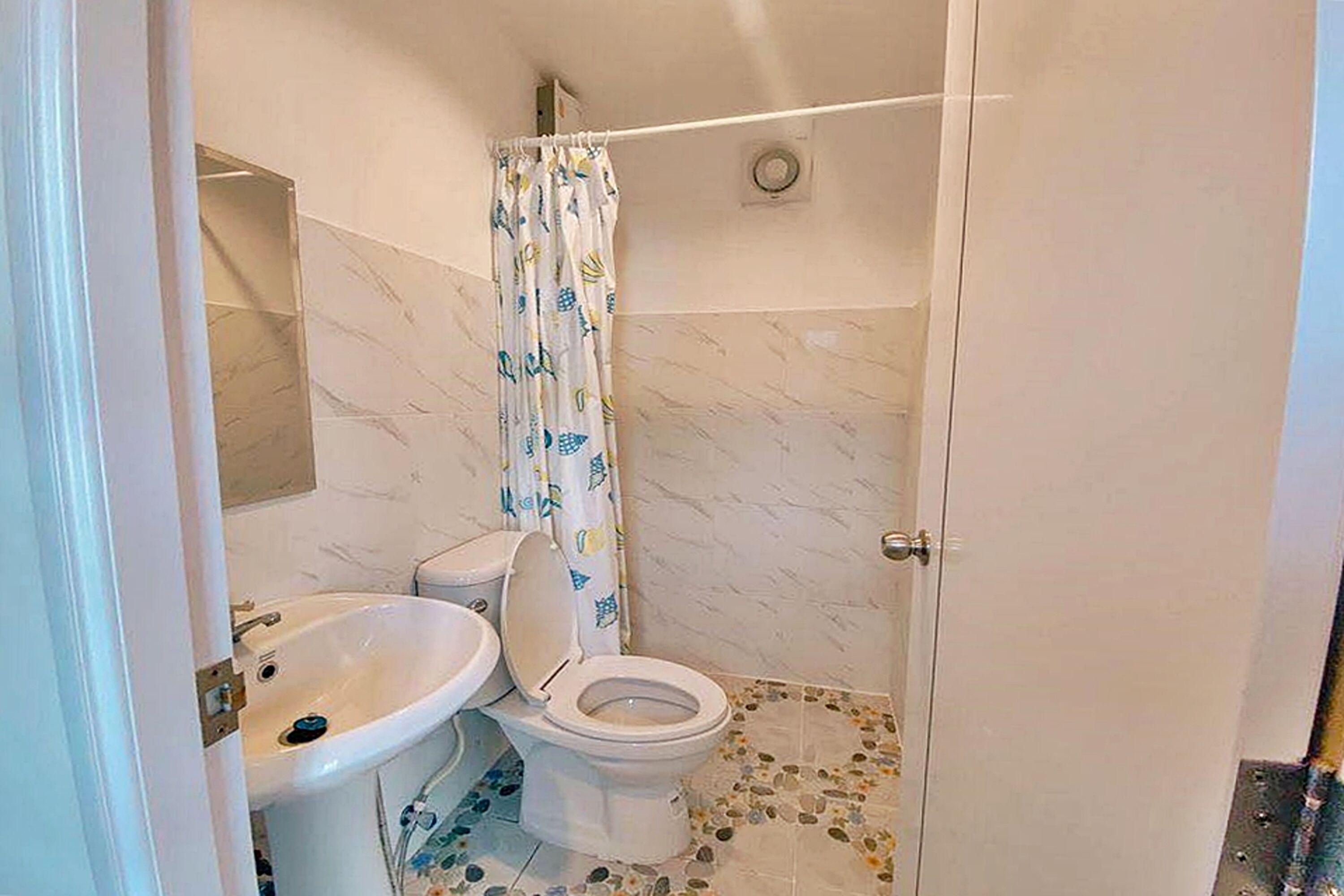 A bathroom with a toilet, sink, and shower.