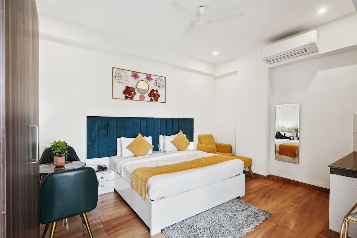 A modern bedroom with a bed, bedside table, chair, and a decorative wall piece.
