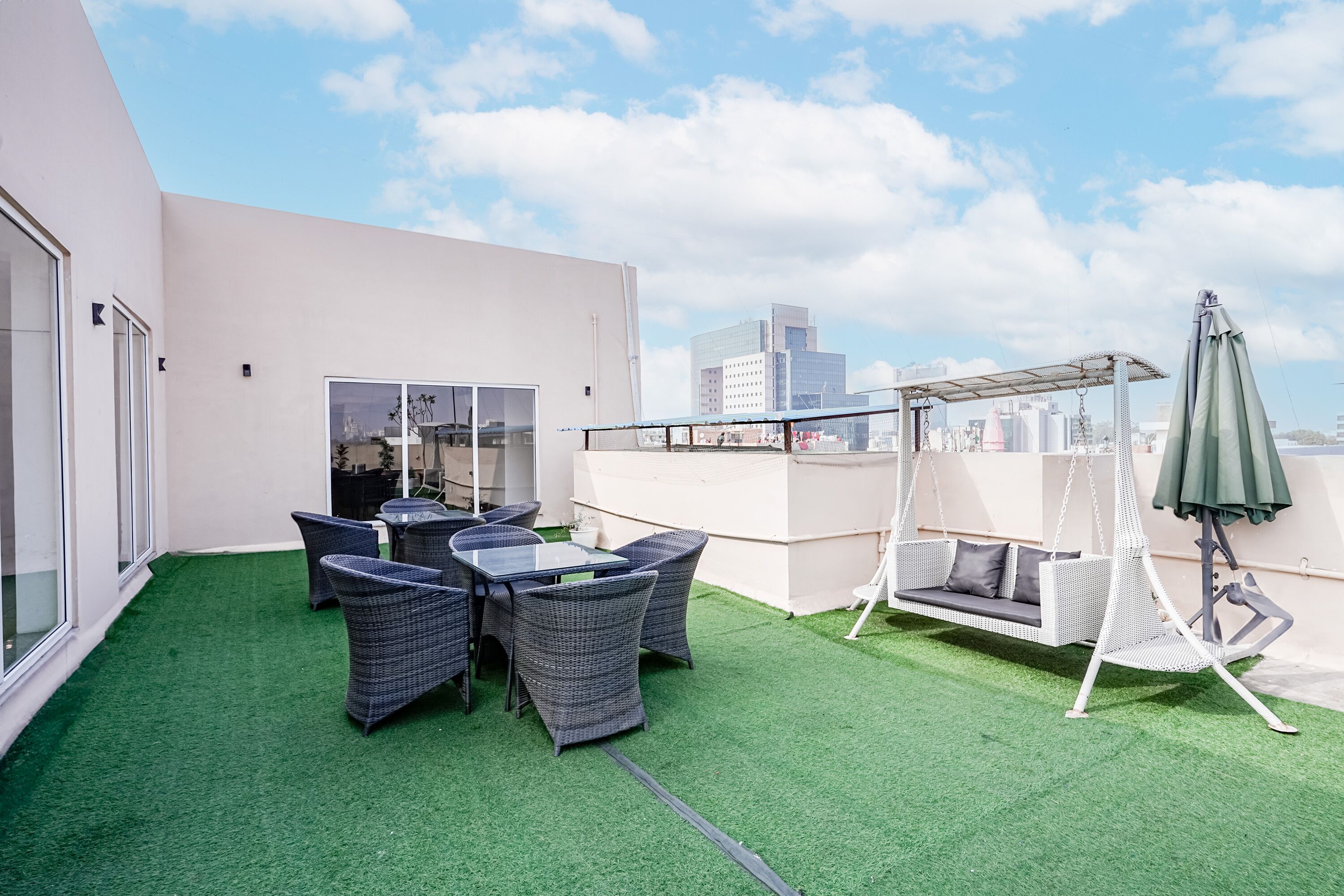 A rooftop terrace with a table and chairs, a swing, and a pergola.