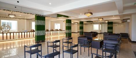 Un vestíbulo amplio con mostrador de recepción, zona de estar y columnas decorativas.