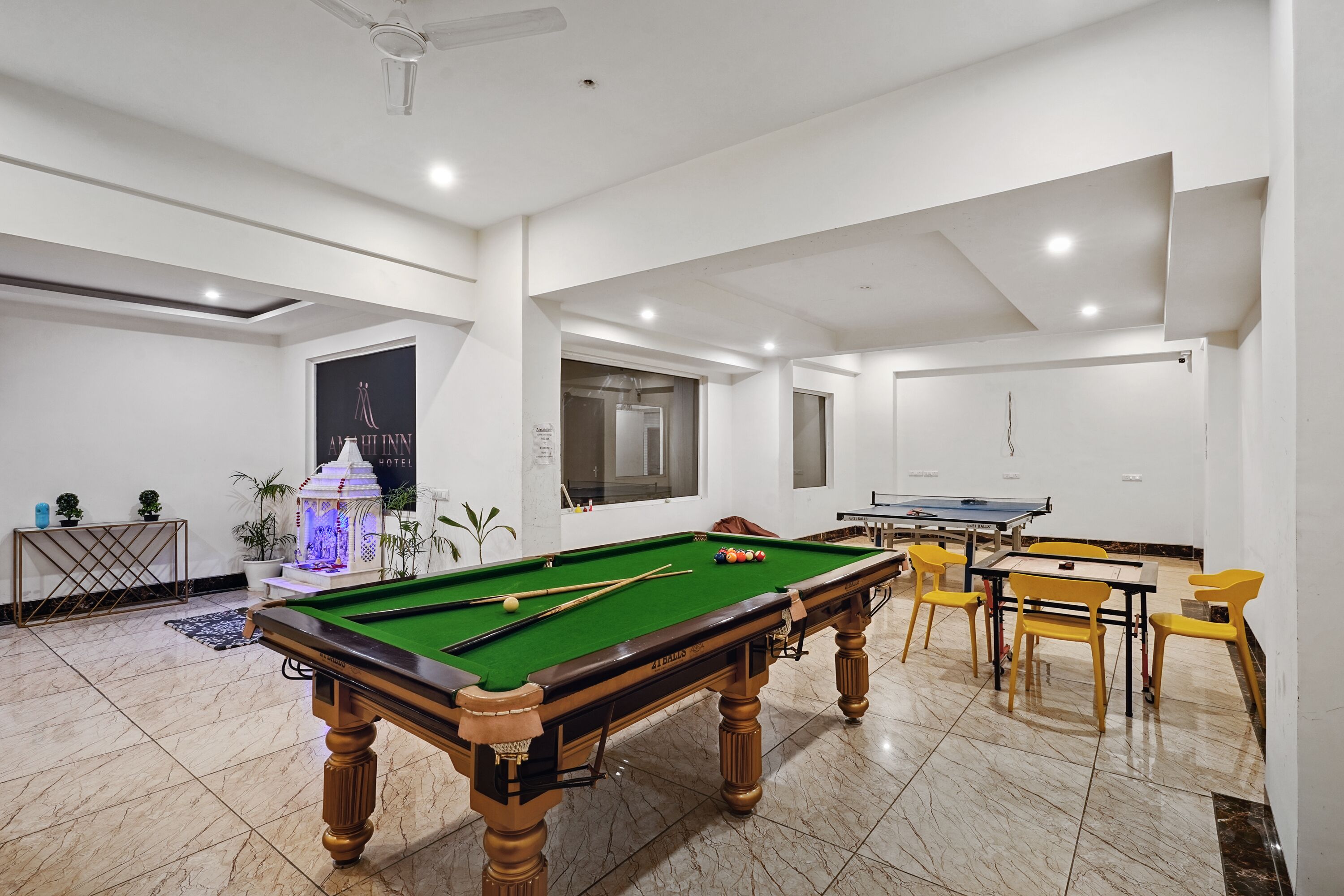 A pool table with yellow chairs, a ping pong table, and a billiards rack.