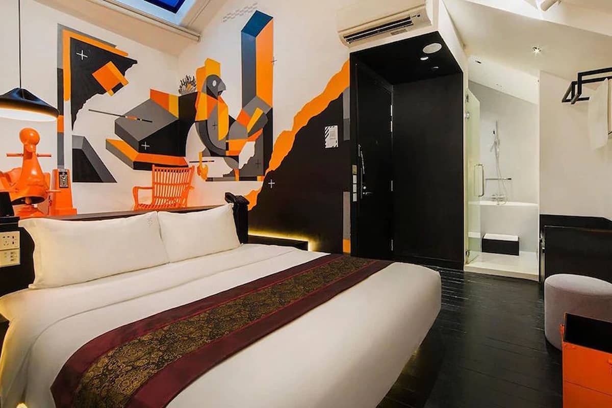 Une chambre d’hôtel moderne dotée d’un grand lit, d’un bureau et d’une salle de bain avec une douche en verre.