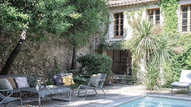 A poolside area with lounge chairs, a stone wall, and a building with windows. - Gîte Canterane, Petite Maison Provençale Rattachèe à Maison Sumiane, 4 Couchages (Brignoles)