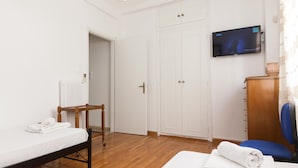 Ein Hotelzimmer mit Bett, Sessel, Fernseher und Kleiderschrank.