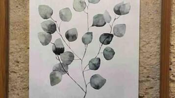 A framed botanical illustration of Eucalyptus leaves on a textured wall.