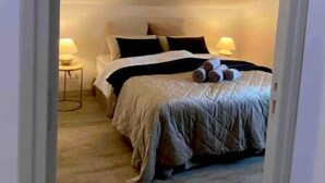 Ein Schlafzimmer mit einem Bett, Kissen, einem Nachttisch mit Lampe und zusammengerollten Handtüchern auf dem Bett.