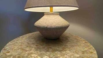 Une lampe dotée d’un abat-jour texturé, posée sur une table ronde dont le plateau présente un motif décoratif.