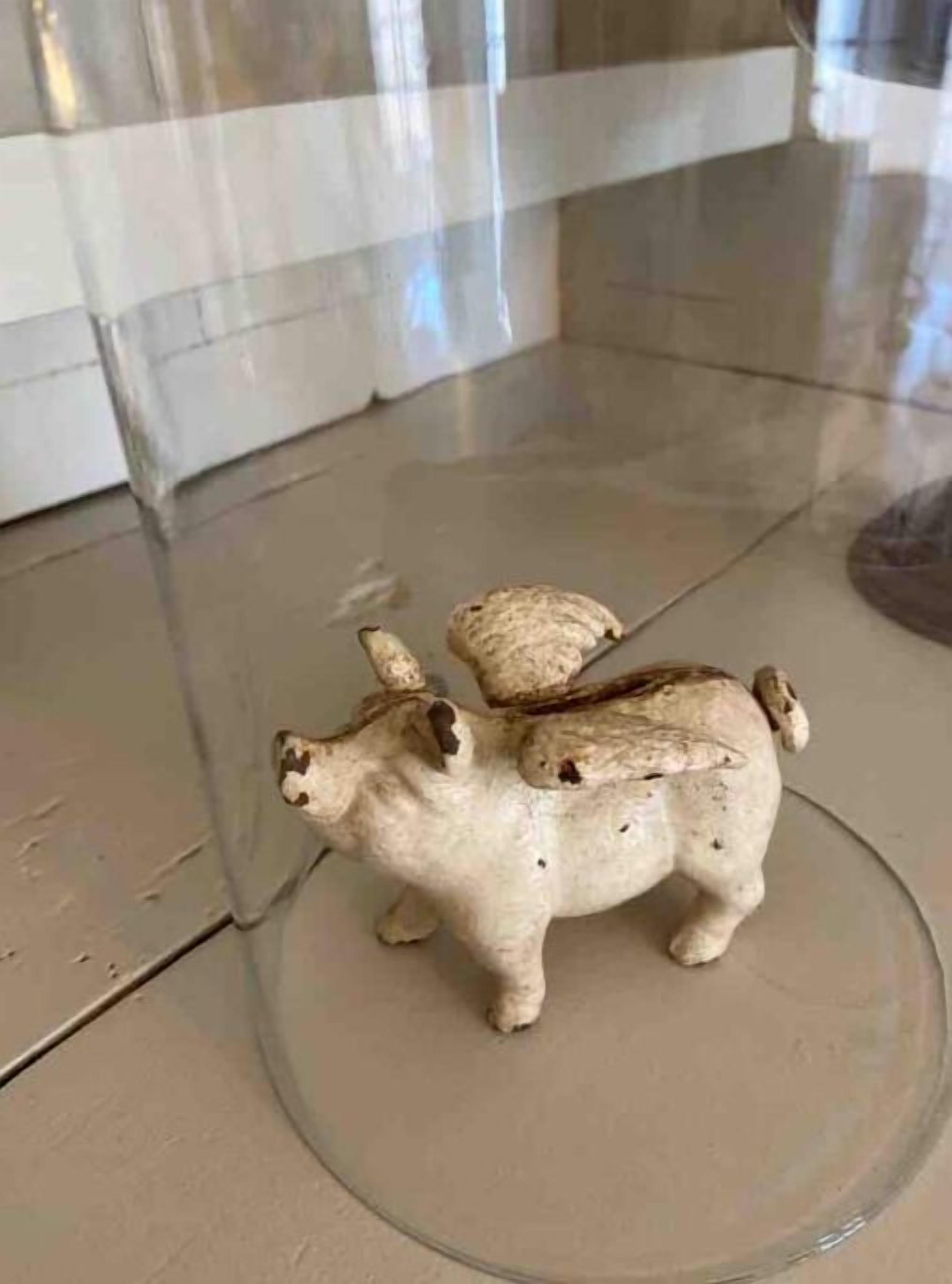 A glass display case containing a small, white figurine of a bull.