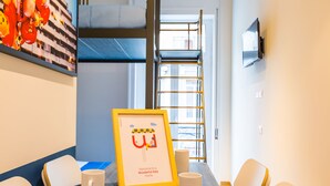 A room with a bunk bed, a ladder, a framed welcome sign, and a table with chairs and a mug. - Central Station Apartments & Suites by Wonderful Italy (Naples)