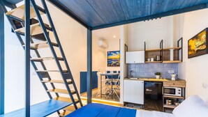 A compact room with a bed, a kitchenette, a dining area, and a staircase. - Central Station Apartments & Suites by Wonderful Italy (Naples)
