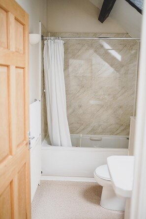 Bathroom features a bathtub, glass-enclosed shower, and toilet.