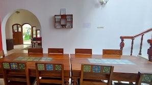 Un comedor con una mesa y sillas de madera, un refrigerador y una estantería.