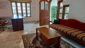 Una sala de estar con un sofá, una mesa de madera, un sillón rojo y un escritorio.