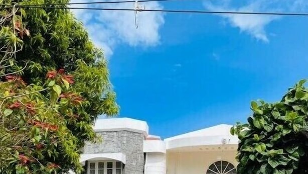 Un hotel con fachada de piedra, exterior blanco y un ventanal grande.