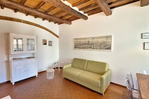 A room with a wooden ceiling, a green sofa, a white cabinet, and a framed cityscape picture on the wall. - Casa Mojito, apartment in the Santa Croce district (Firenze)