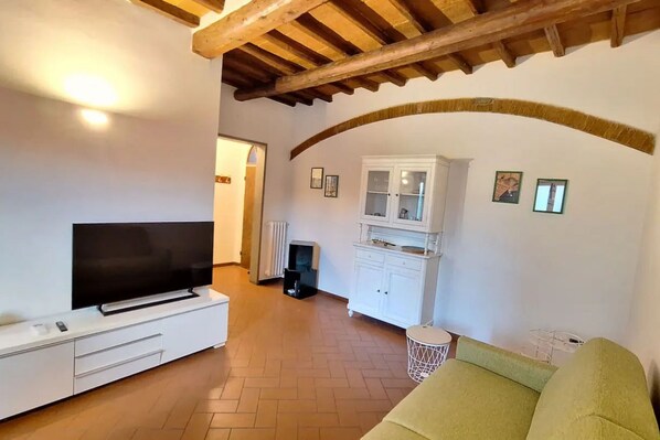 A living room with a flat-screen TV, white cabinets, a green sofa, and a wooden ceiling. - Casa Mojito, apartment in the Santa Croce district (Firenze)