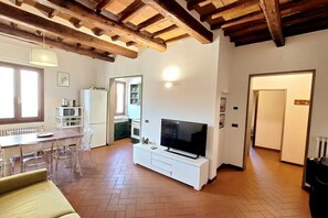 A living room with a TV, dining table, chairs, and a sofa. - Casa Mojito, apartment in the Santa Croce district (Firenze)