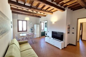 A living room with a sofa, a TV, a dining area with a table and chairs, and a kitchen in the background. - Casa Mojito, apartment in the Santa Croce district (Firenze)