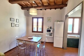 A kitchen with a wooden table, chairs, a refrigerator, and a microwave. - Casa Mojito, apartment in the Santa Croce district (Firenze)